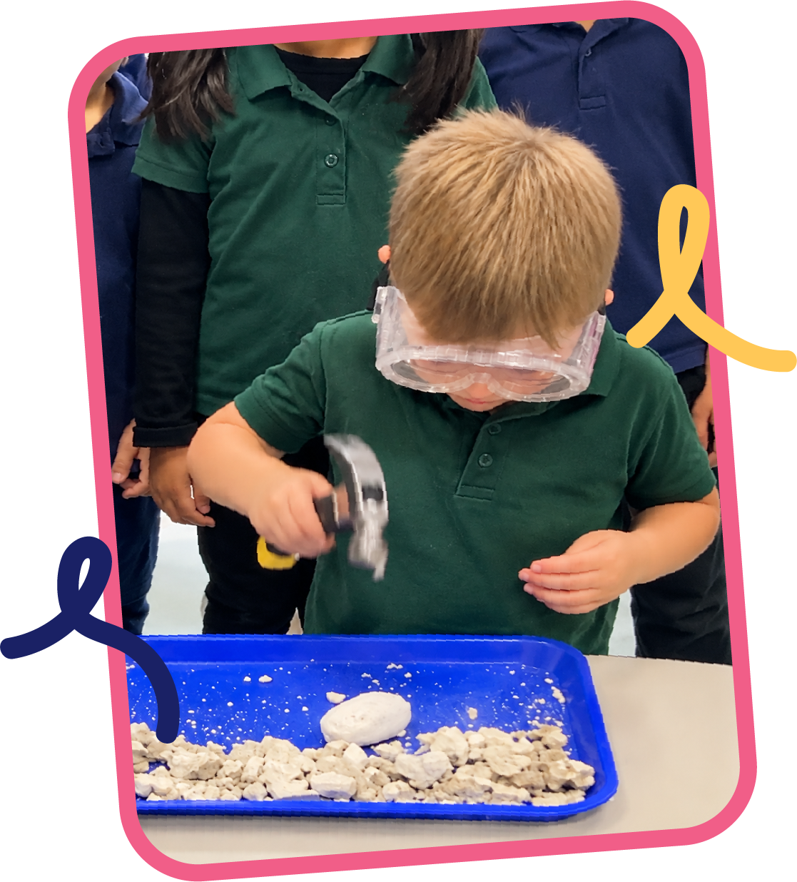 Young boy wearing safety goggles using a hammer to break apart rocks during a geology STEM activity at STEM Bright Beginnings childcare and daycare in Leander, TX