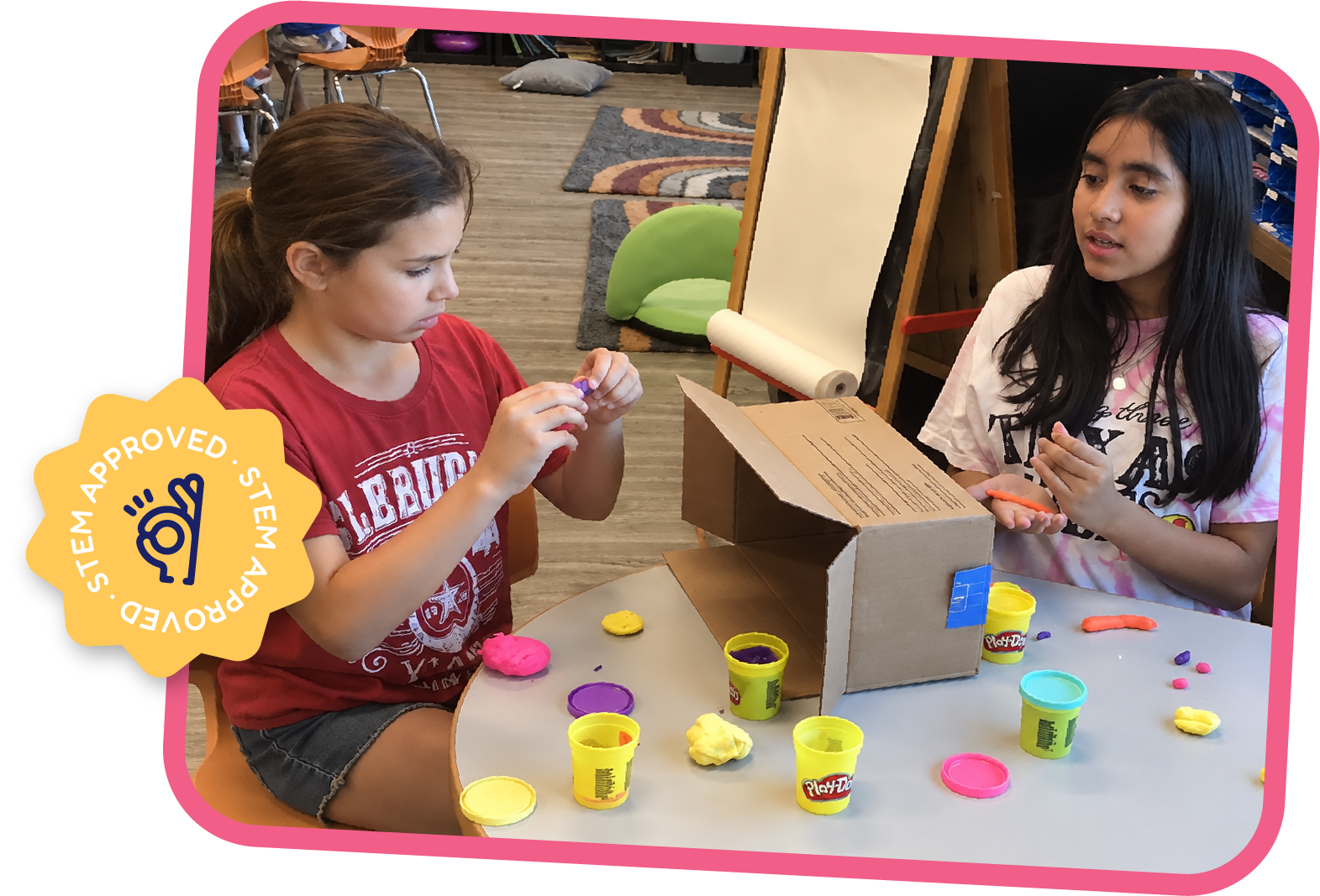 Students molding colorful Play-Doh figures to decorate a cardboard box structure during an After School STEAM activity at STEM Bright Beginnings in Leander, TX