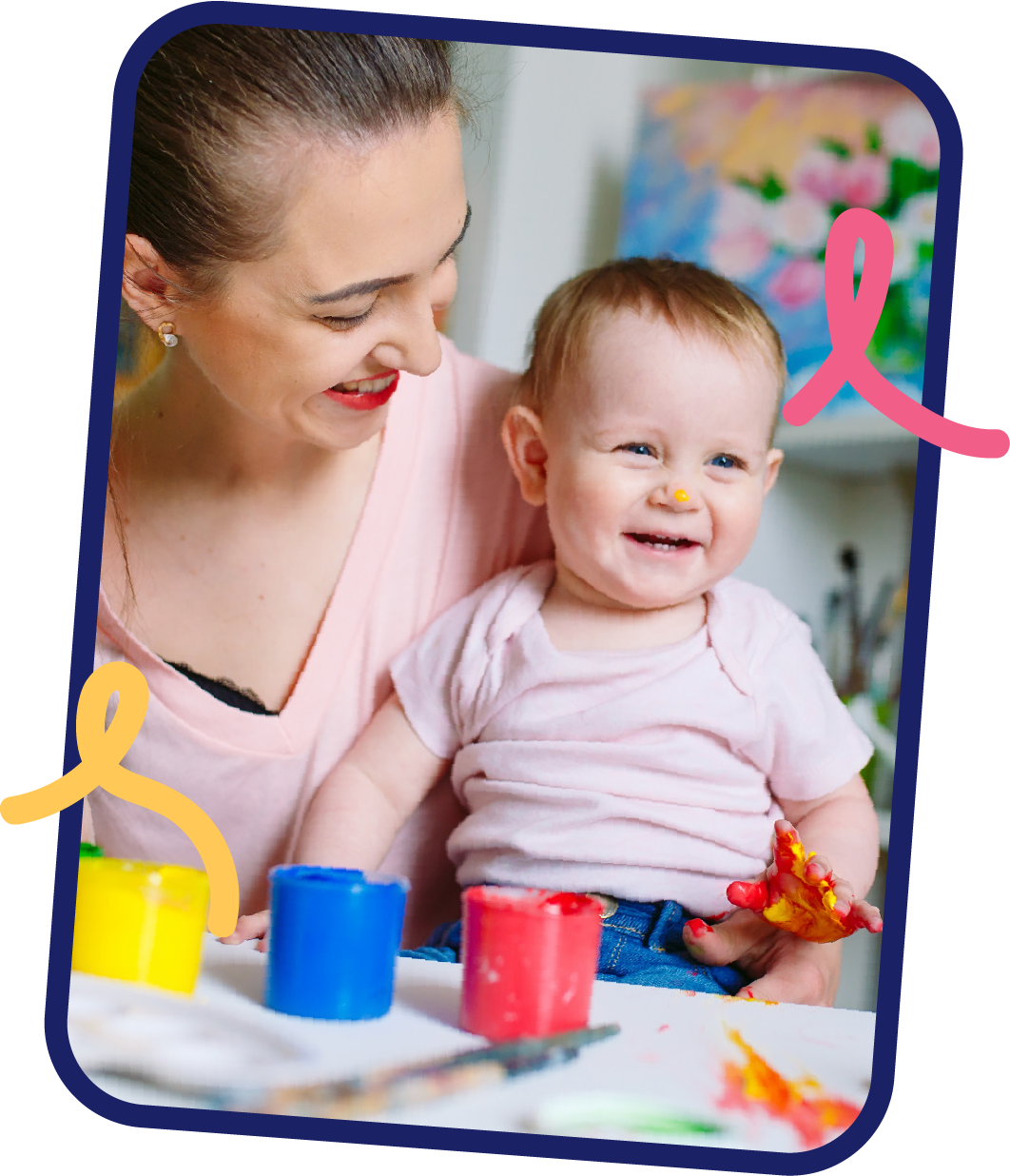Caregiver smiling at a happy baby with paint on their hands, part of sensory play in the Discoverers infant program at STEM Bright Beginnings in Leander, TX