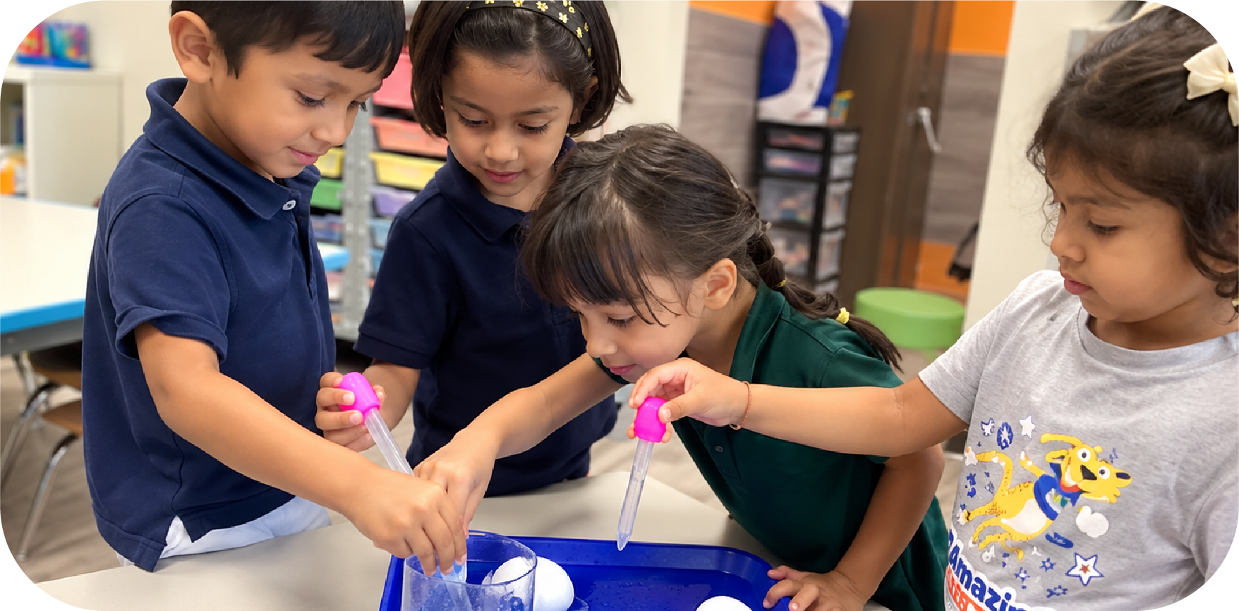 Young children conducting a hands-on STEM experiment with color droppers and water at STEM Bright Beginnings childcare and daycare in Leander, TX