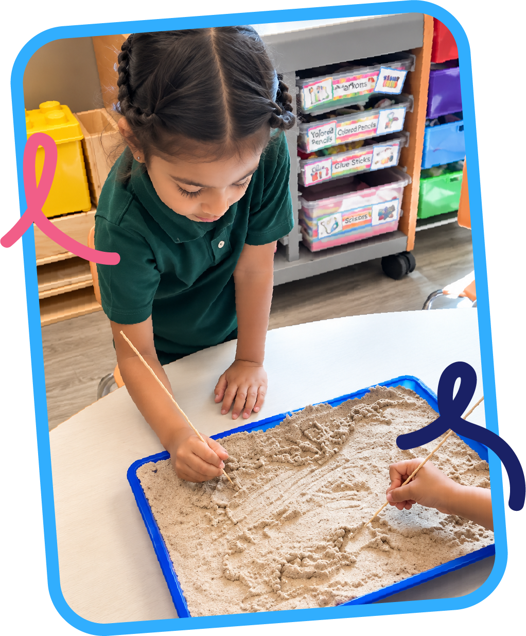 Young girl using a stick to create patterns in kinetic sand during a sensory writing activity at STEM Bright Beginnings childcare and daycare in Leander, TX
